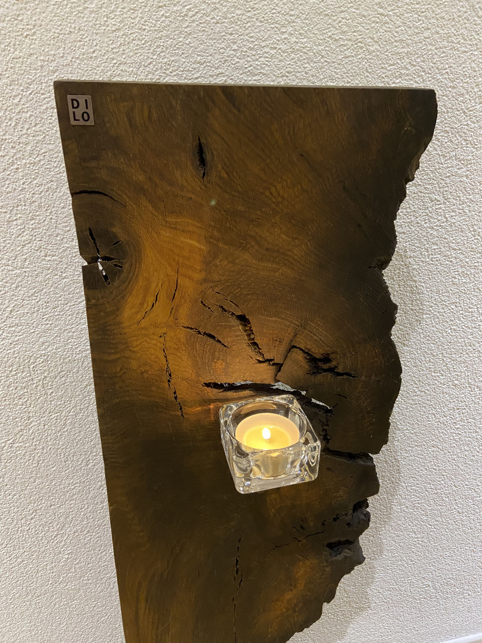 Das Brett sieht aus wie ein Gesicht. Das Astloch ist das Auge. Bei diesem sind 5 geschwärzte Stahlstifte montiert um eine Kerze zu platzieren.