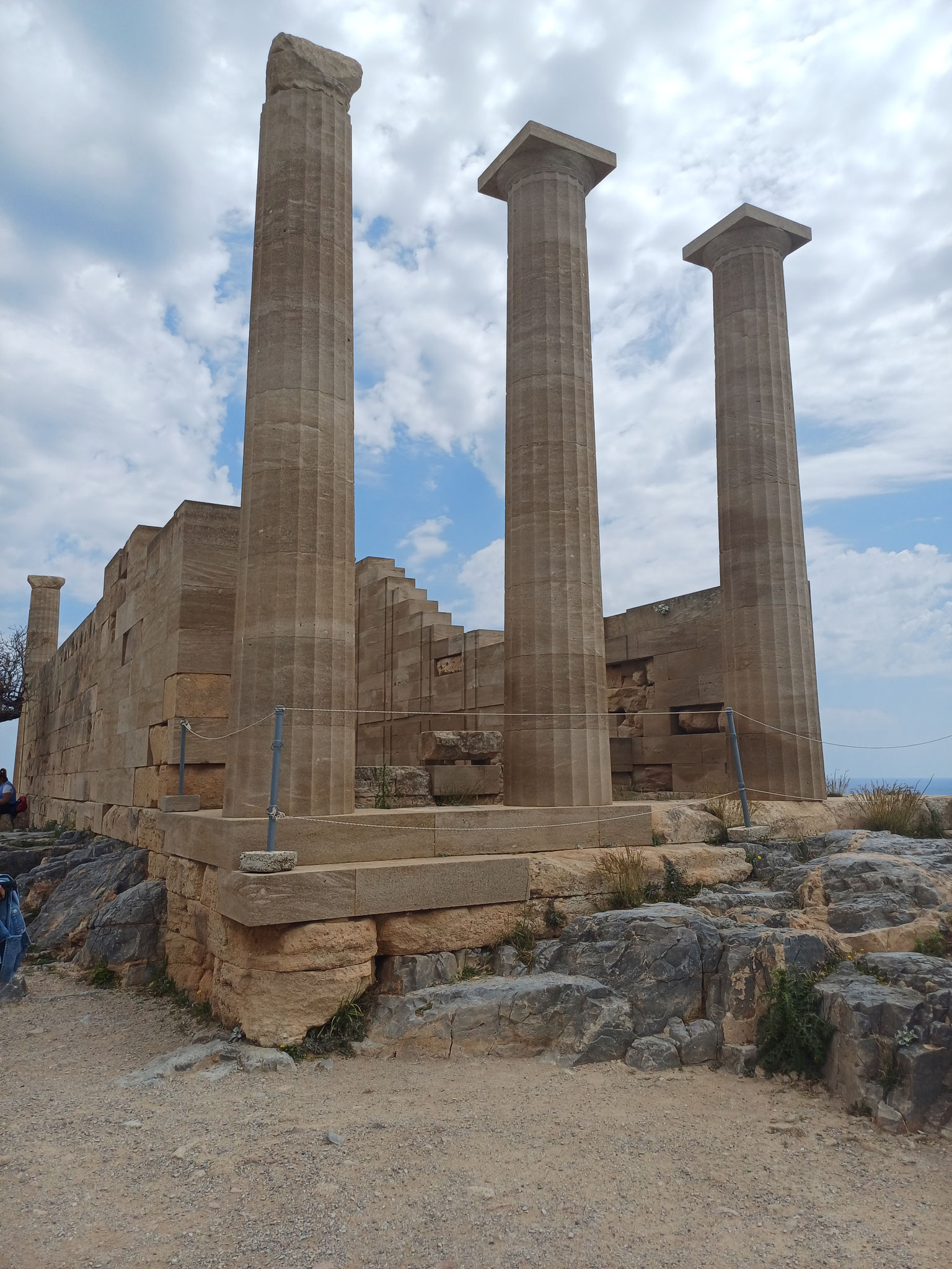 Man sieht drei Säulen, die auf der Akropolis von Lindos auf dem obersten Punkt stehen.