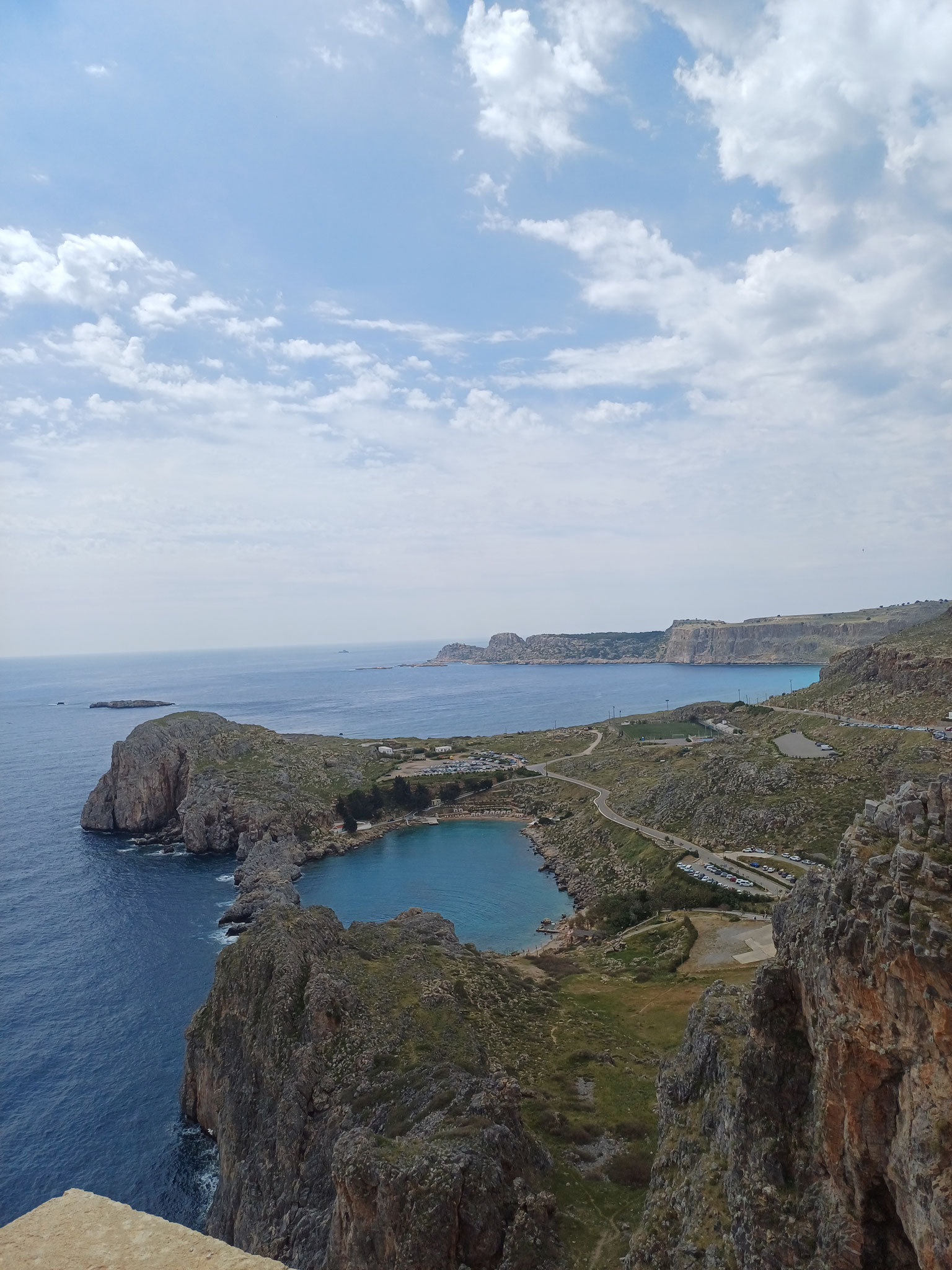 Ausblick auf eine blaue Bucht, die von Felsen umrahmt ist.