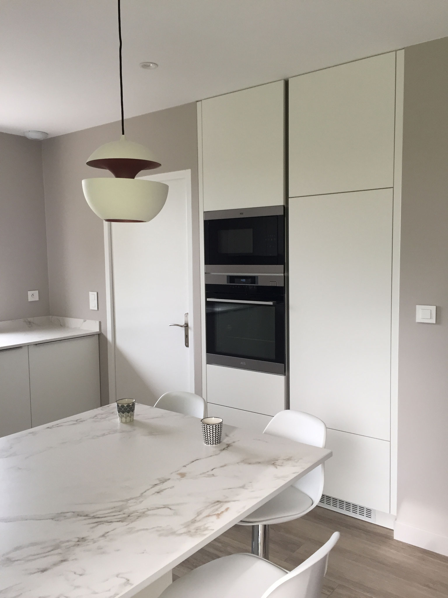 cuisine blanche design ouverte plan en DEKTON avec ilot  colonnes sans poignées et luminaires here come the sun