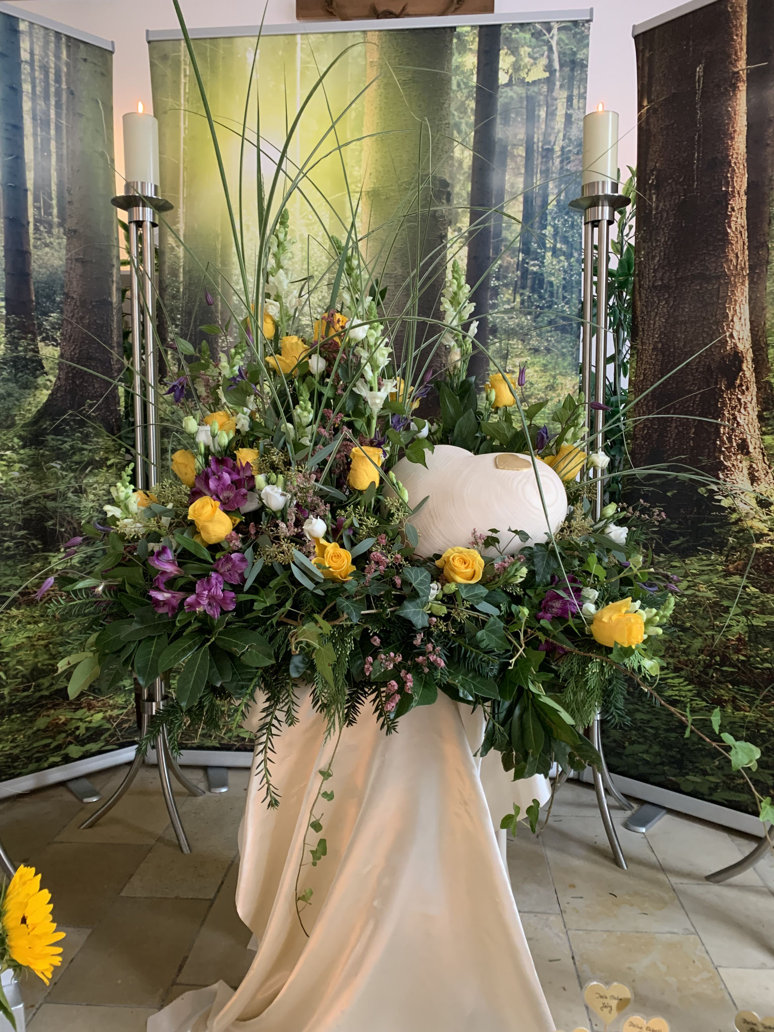 ein Holzherz im Blumenbett in der Friedhofshalle Altusried