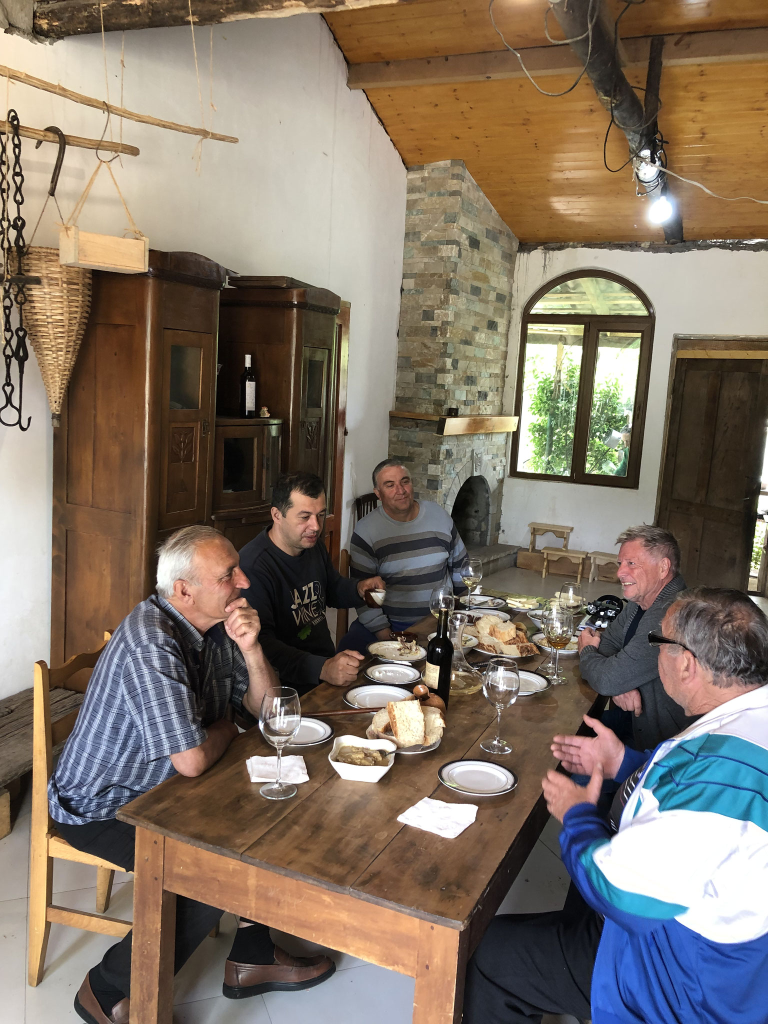 aan tafel met buren en verre buren die hem over hun oude wijngaard komen vertellen