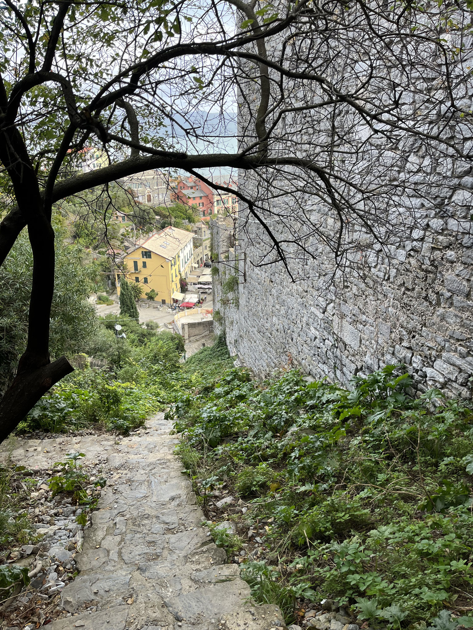 Ein sehr ungepflegter Treppenweg führt an der hohen Burgmauer entlang …