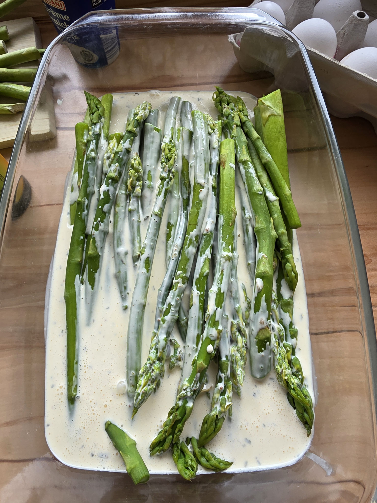 Geschichteter grüner Spargel in der Auflaufform mit cremiger Füllung