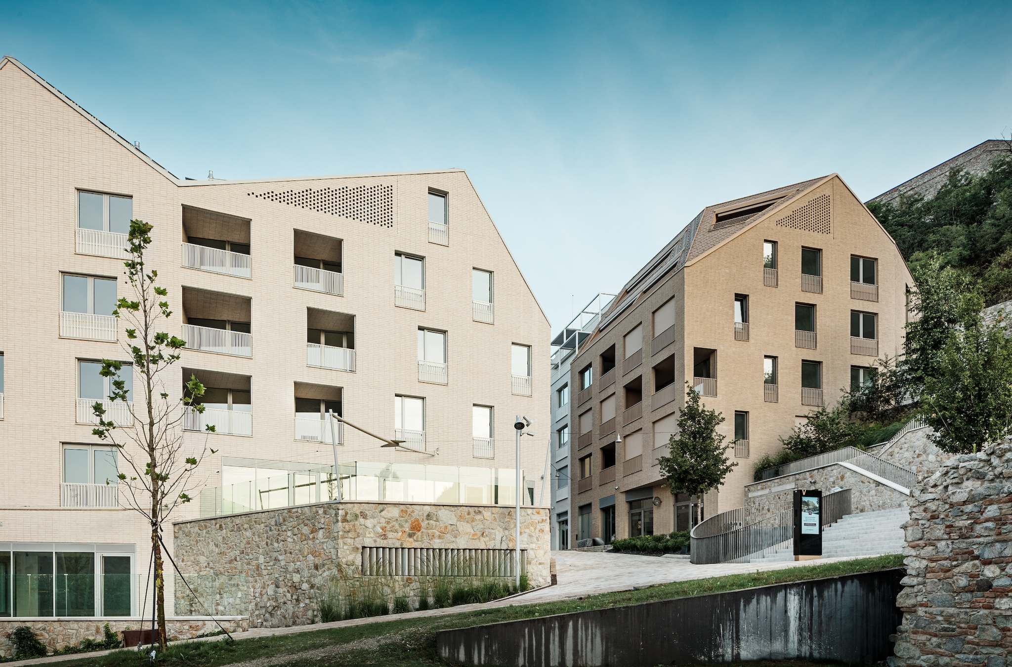 Das gestalterische Leitbild folgt einer One-Skin-House-Idee mit monochrom erscheinenden Dächern und Fassaden in unterschiedlichen Texturen und Materialien. Insgesamt vier Hauptbaukörper erhielten 16 Fassadenvarianten.