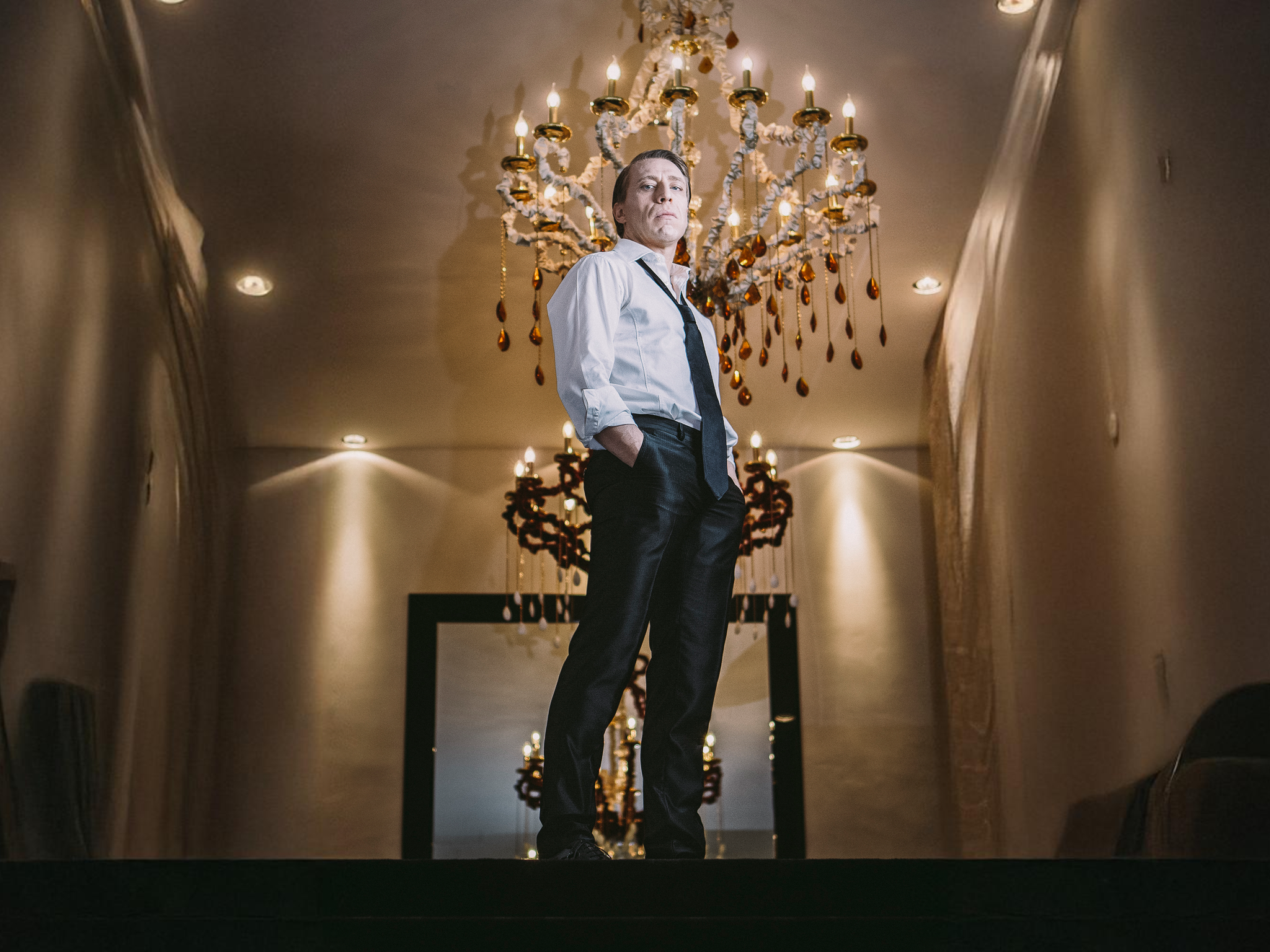 Ottaviano Blitch, actor and performer, glamour full-length portrait standing before an ornate golden chandelier, attore performer ritratto glamour scenografico