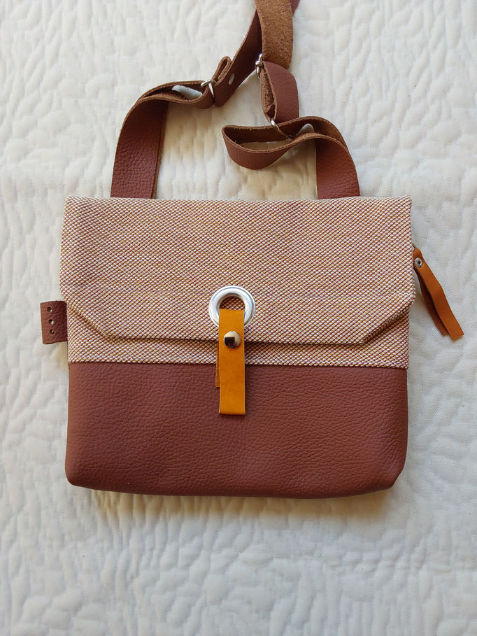 stof/leer( b.25cm x h. 22 cm) extra voorvak. sluit met rits. verstelbare schouderband € 70,--