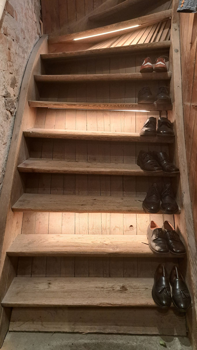 Eine alte Holztreppe führt in den oberen Stock - man beachte die edlen Herrenschuhe auf den Stufen