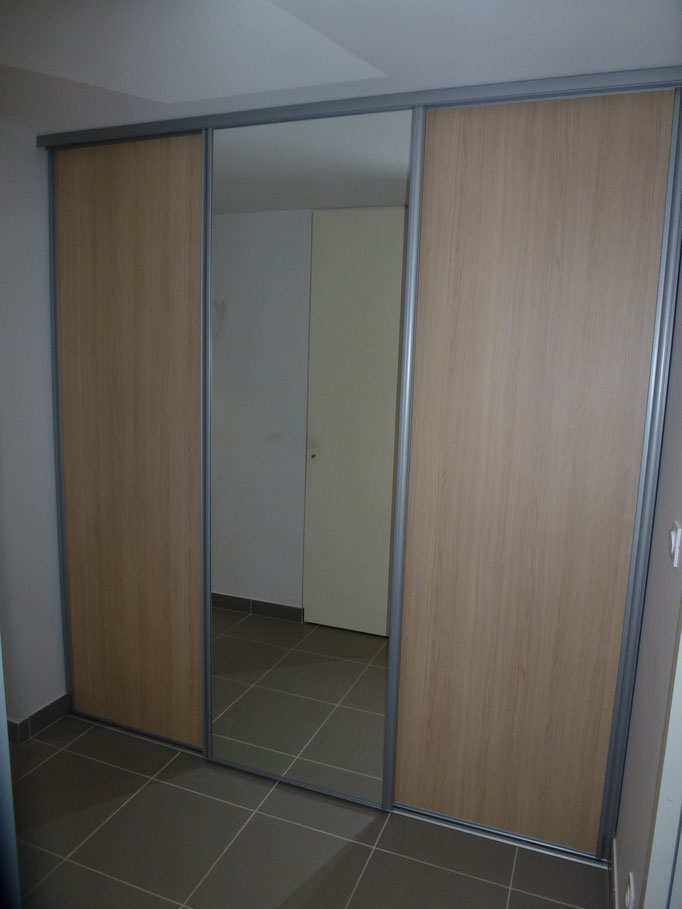 Placard avec trois portes - miroir au milieu et porte finition chêne.