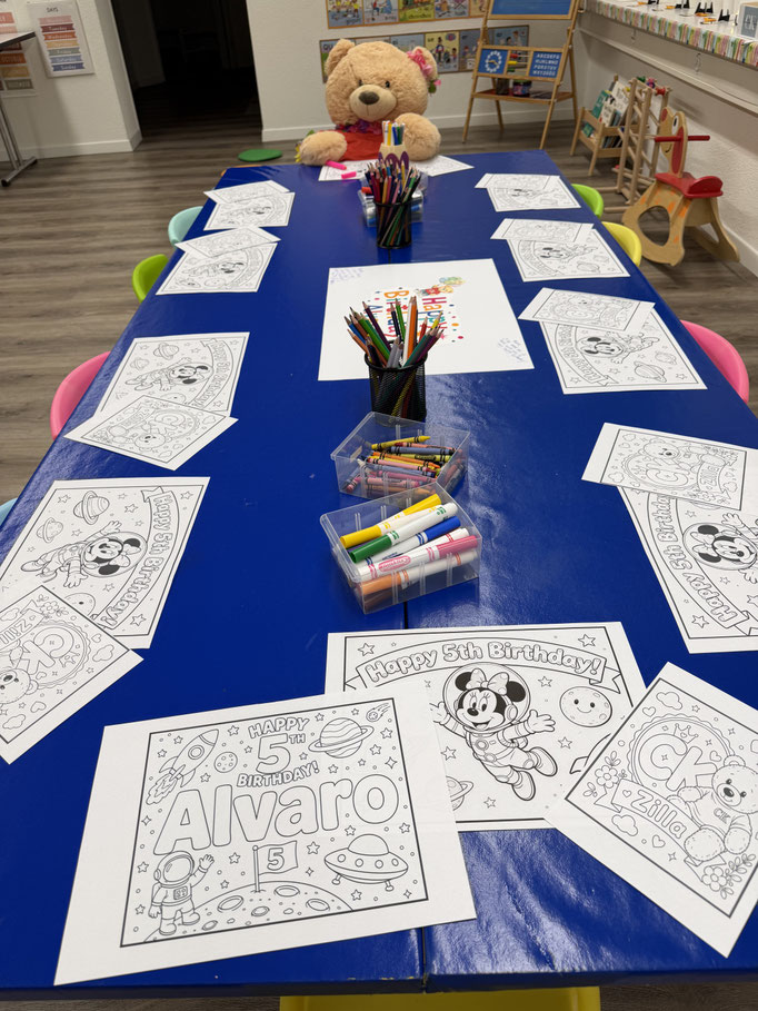 Birthday party table set up with colouring activities and the Custom Kids mascot, Zilla.