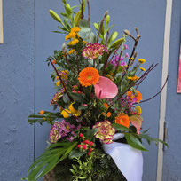 Farbenfrohes, hohes Gesteck mit Gerbera, Lilien u7nd Zweigen in der Blumenhütte München