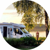 Weißes Wohnmobil unter Baum vor See 2025