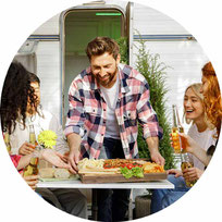 Freunde an Campingtisch vor Wohnmobil 2025