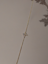 MOKOŠEV Luxusschmuck, feines goldenes Armband mit zartem Blütenanhänger auf neutralem Hintergrund.
