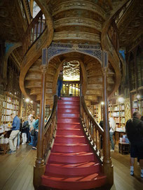 Buchhandlung Lello: Geschnitzte Holztreppe, die sich in zwei Aufgänge verzweigt und in den ersten Stock windet