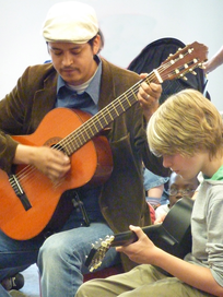 Ein erwachsener Gitarrist spielt gemeinsam mit einem Kind Gitarre.