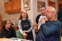 Stefan Gräßler zeigt Josefine, Jule und Jamie, wie ein Gesicht bemalt wird. Dazu schneidet er zur Verdeutlichung auch Grimassen. Bild: Christof Heyden