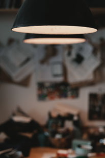 Spezialistenwissen für Mantel Liebhaber: Aufnahme von Arbeitsleuchten über dem Zuschneidetisch im Atelier von Manuela Leis