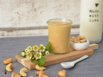 Cashewmus im Glas auf Holzbrett mit Milchflasche