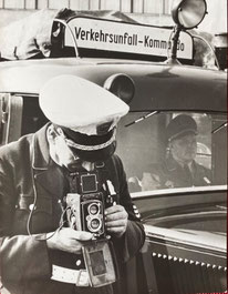 Verkehrspolizist (weiße Mütze) bei der Unfallaufnahme