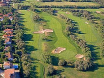 Luftaufnahme eines Golfplatzes mit mehreren Sandbunkern und angrenzenden Ferienhäusern