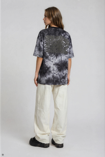 model wearing relaxed boxy fit light grey batik t-shirt with a black bold Letter vertigo print on the back
