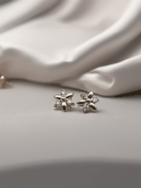 MOKOŠEV luxury jewelry, delicate flower earrings with sparkling stones on soft white satin.