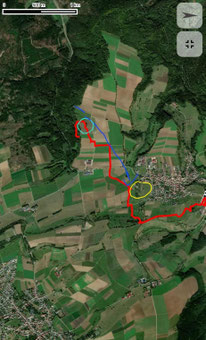 Luftaufnahme einer Landschaft mit Feldern, Waldflächen und einem Dorf, darauf eingezeichnete rote, blaue und gelbe Linien und Kreise.