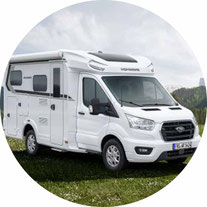 Wohnmobil in weiß mit Alkoven fährt auf Straße rund 2026