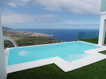 Blick vom Apartment vorbei an Palmen und dem Pool bis zum Horizont über dem Meer.