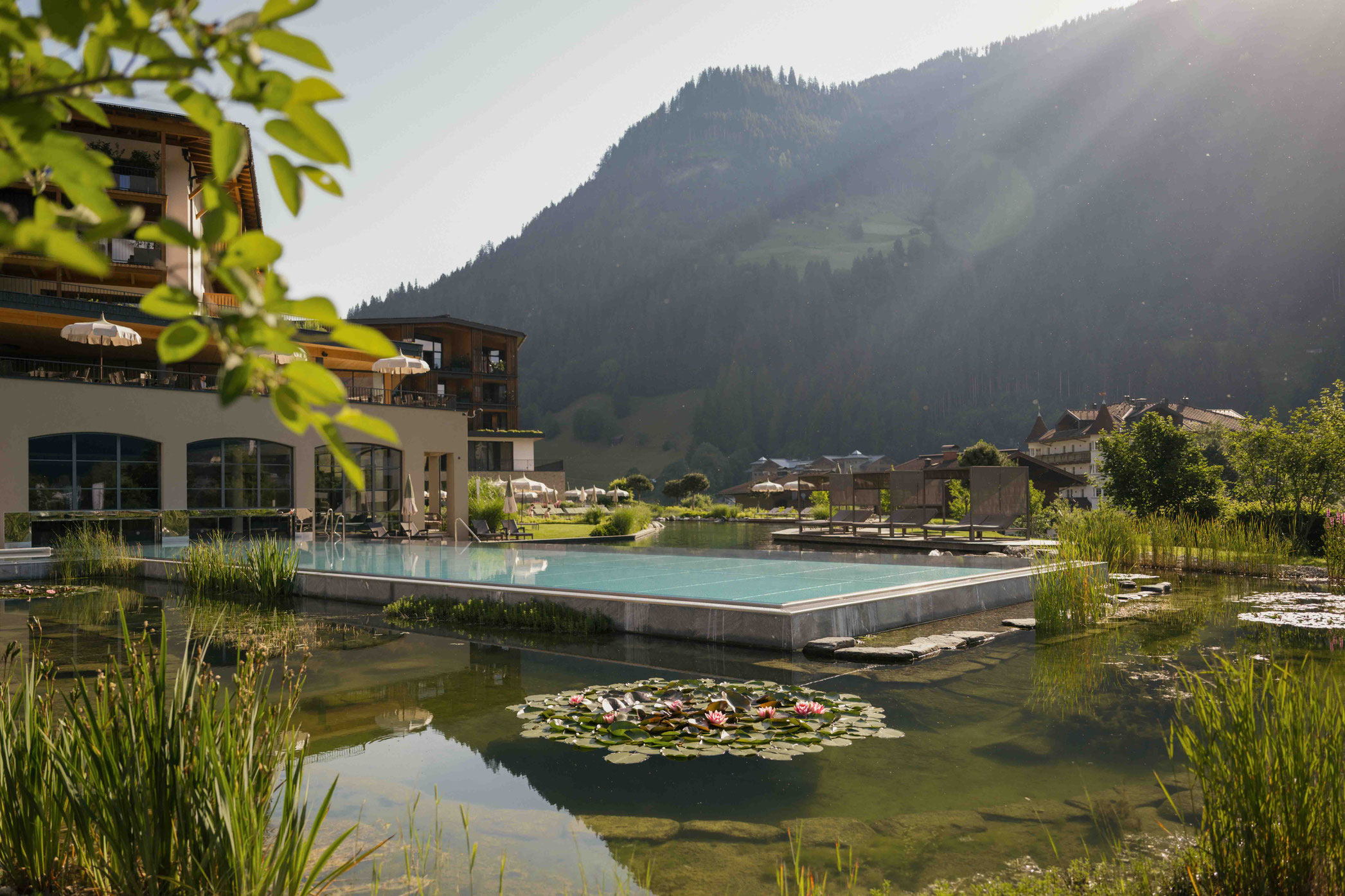 Architektur - Außenansicht mit Outdoorpool und Badeteich - NESSLERHOF in Großarl • 5-Sterne-Wellnesshotel im Salzburger Land _fullwidth-story-splash