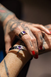 Photographie d'un bracelet en argent et améthyste sur le bras du modèle qui le tient. Le modèle porte une bague du même style et tient le bracelet