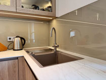 Flächenbündig eingebaute Spüle in einer Dekton-Arbeitsplatte mit integrierter Abtropffläche, die bis in die Raumecke geführt ist und den vorhandenen Platz optimal nutzt