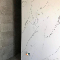 Salle de bain moderne, tendance avec un carrelage et une faïence imitation marbre robuste, solide et facile d'entretien. Pose de carrelage imitation marbre tendance en grands carreaux pour la salle de bain dans une douche à l'italienne.