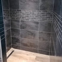 Carrelage douche design, noir et bois dans une salle de bain moderne avec douche à l'italienne et caniveau de douche à l'italienne. Douche design moderne et tendance.