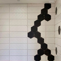 Décor faïence original et unique dans une salle de bain. Créer un décor dans une salle de bain. Salle de bain noire et blanche design et tendance. Carrelage à la mode pour une rénovation de salle de bain.