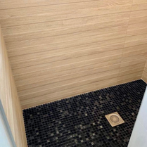 Bac à douche à l'italienne noir. Faïence noire et imitation bois pour une salle de bain tendance et design. Carrelage pour douche à l'italienne et carrelage pour une petite salle de bain.