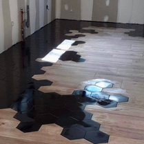 Carrelage moderne noir et imitation parquet dans une pièce de vie. Carrelage tendance pour une cuisine design avec du carrelage noir. Carrelage hexagonal incrusté avec imitation parquet. Dernière tendance sol pour cuisine.