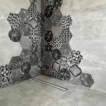 Bac à douche à l'italienne design et tendance facile d'entretien. Mur design salle de bain avec faïence noire et carreaux de ciments incrusté pour un décor unique et design dans une rénovation de salle de bain.