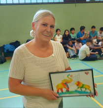 Ute Gezer freut sich über das farbenfrohe Bild mit einem Volleyball spielenden Elefanten und einem Volleyball spielenden Löwen