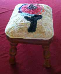 Hooked rug with hand-dyed wool attached to footstool.