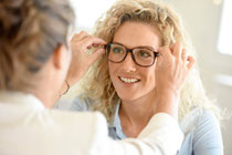 Frau bekommt einen neue Gleitsichtbrille vom Augenoptiker aufgestzt