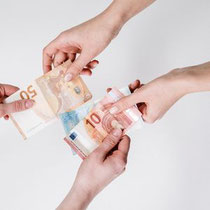 Photo de 4 mains échangeant des billets de banque. 