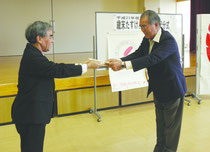 歳末助け合い配分金が栽会長(右)に託された=市健康福祉センター=
