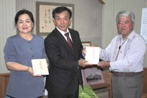玉津教育長に「白保村以北の旧村々」を手渡す石垣会長(右)=31日午前、市立図書館