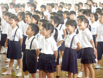 終業式で教諭らのダンスに笑う児童たち=19日午前、登野城小学校