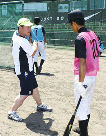 中学生にバッティング指導する久慈照嘉さん(左)=市中央運動公園野球場