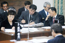 教科書問題を追及する野党に対し、当局と答弁を調整する玉津教育長(右)、石垣委員長=19日、市議会