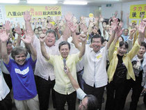 4期目の当選を決めバンザイ三唱する高嶺氏(中央右)と支持者=10日夜、選対本部