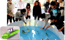 手作りの「ポンポン船」を水槽に浮かべる児童=15日午前、伊野田小学校